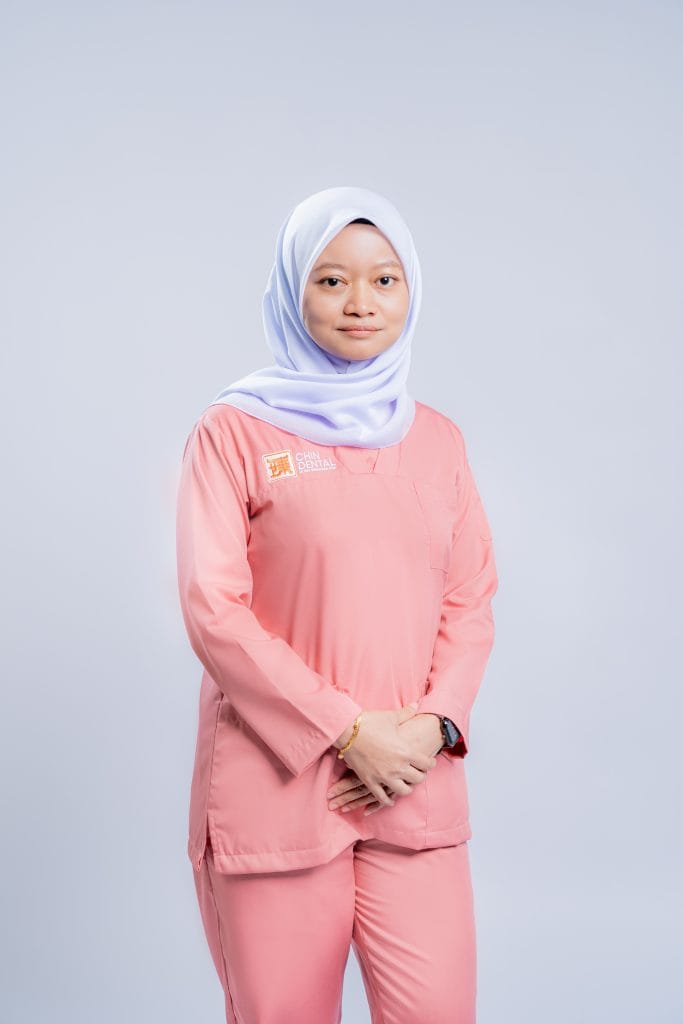 Friendly Asian female dental professional wearing pink scrubs and a white hijab at Chin Dental Clinic.